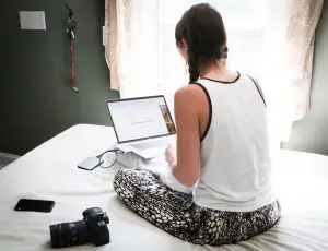 woman sitting on bed with laptop