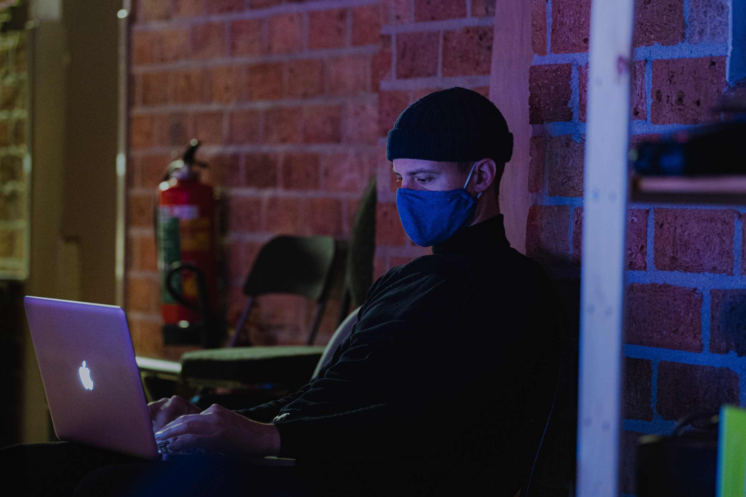 Man dressed as burglar working on a computer in a dark room