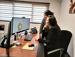 Two ETTE technicians in an office analyzing a pie chart graphic in a computer monitor